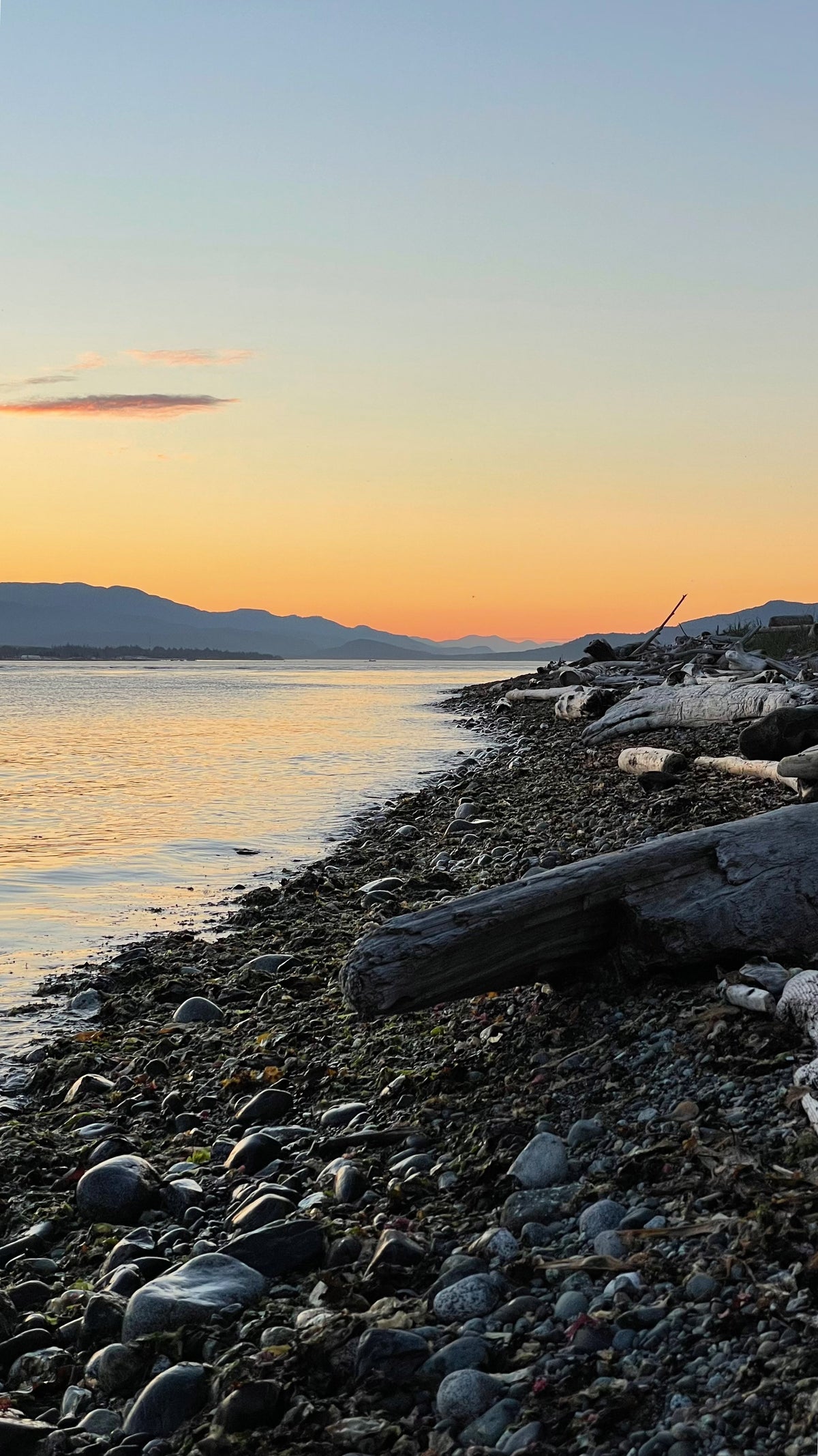 Sunset over a calm body of water with a rocky shoreline on Vancouver Island